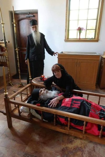 Doamna Sarah Atwood la căpătâiul soțului ei, p. Efrem. În spate p. Stareț Paisie, Egumenul Mănăstirii „Sf. Antonie” din Arizona